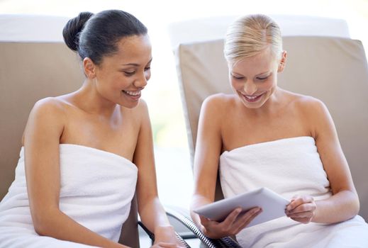 What treatment are you gonna get. two young women looking at a magazine in a beauty spa
