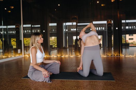 Yoga exercises. A personal trainer teaches a woman yoga classes in the gym.