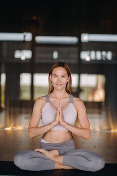 The girl does yoga. A woman in sports clothes does yoga exercises in the gym.