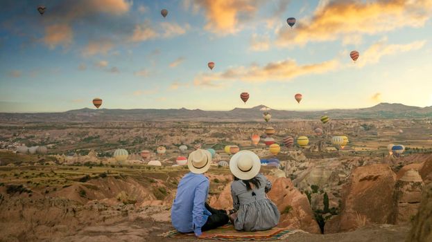 Kapadokya Cappadocia Turkey, a happy young couple during sunrise watching the hot air balloons of Kapadokya Cappadocia Turkey during vacation. Asian women and caucasian men on holiday in Turkey