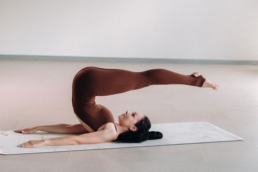 a woman in a brown suit does yoga in a fitness room . Healthy lifestyle, fitness, training, self-care.