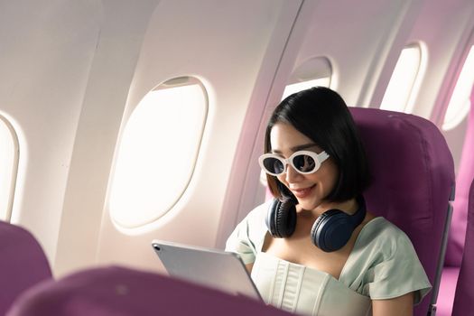 Passenger using tablet computer in airplane cabin during flight. watching series