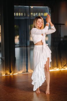 Beautiful smiling girl in a white dress dancing in the gym.