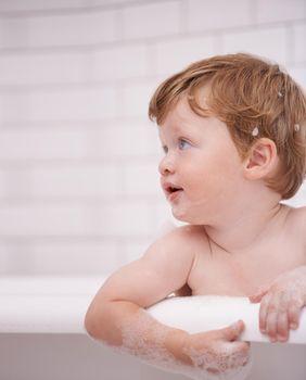 Getting fresh and clean. Tiny red-headed toddler in the bath tub