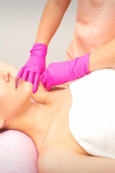 Waxing. Depilation under the armpits of the young woman lying with closed eyes in the spa salon