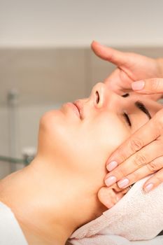 Young caucasian woman with closed eyes getting a facial massage in a beauty clinic