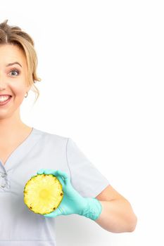 Young Caucasian smiling woman doctor nutritionist holding slices pineapple over isolated white background, breast health concept