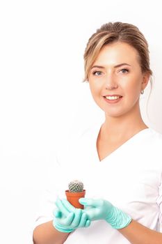 A portrait of a smiling female holds little green cactus in her hands. Hair removal concept