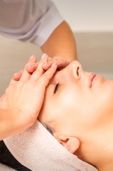 Facial massage. Young caucasian woman with closed eyes getting a massage on her forehead in a beauty salon