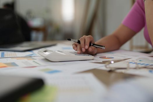 Asian Businesswoman calculating saving account balance with calculator, account and saving concept.