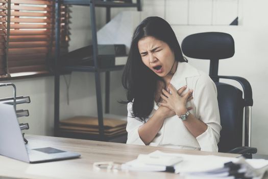 Young business woman working in office suffering from heart attack