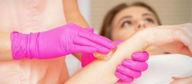 Waxing. Depilation hand and arm of the young woman lying in the spa salon