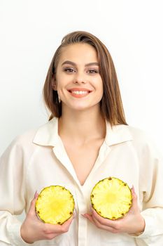 Young Caucasian smiling woman holding slices pineapple over white background, breast health concept