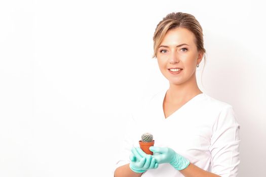 A portrait of a smiling female holds little green cactus in her hands. Hair removal concept