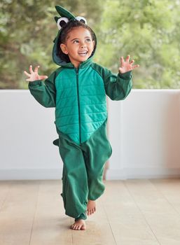 Child, smile and excited in halloween dinosaur costume at home playing role and having fun at party. Happy kid being playful with fantasy character in living room mimic animal actions ready to roar