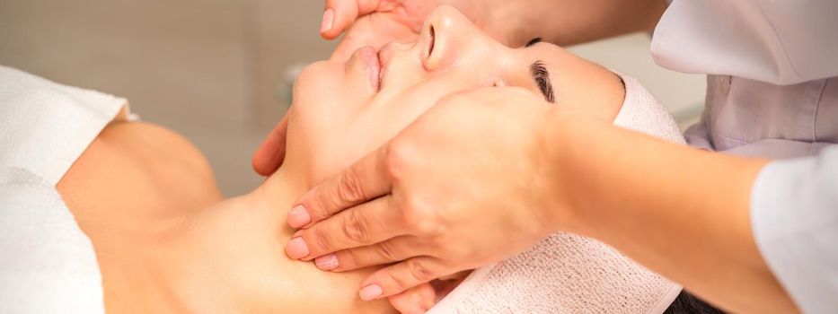 Facial massage. Young caucasian woman getting a massage on her neck in a beauty clinic