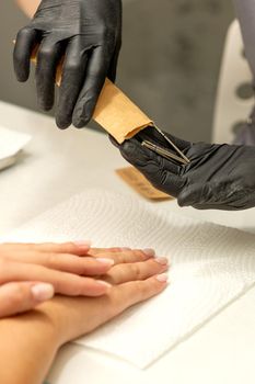 Manicure master takes out manicure tools from a kraft envelope in a nail salon