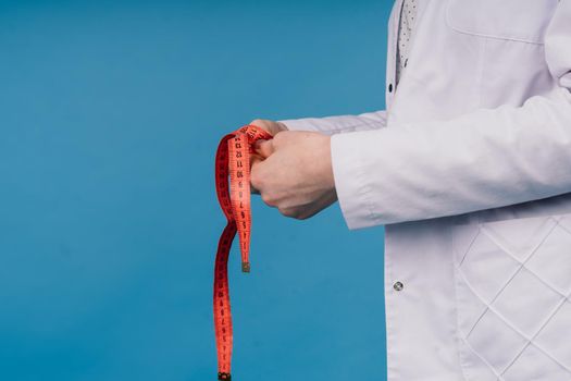 Young beautiful doctor woman in a lab coat, studio shot, blue background