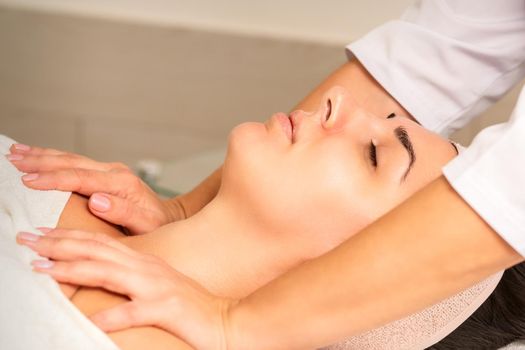 Young caucasian woman with closed eyes getting a chest massage in a beauty clinic