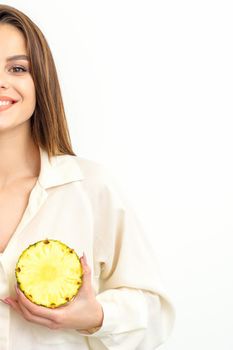 Young Caucasian smiling woman holding slices pineapple over white background, breast health concept