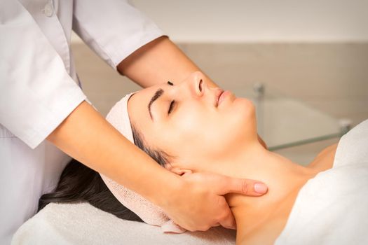 Facial massage. Young caucasian woman getting a massage on her neck in a beauty clinic