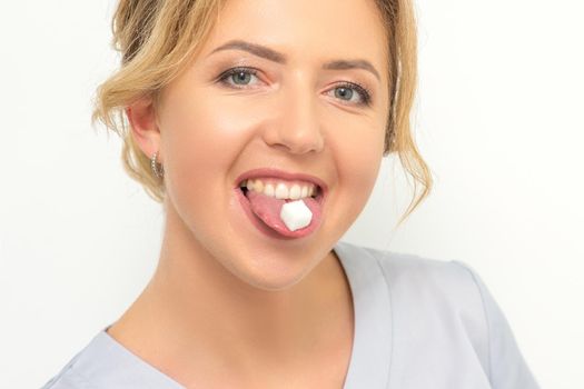 Waxing, depilation, hair removal concept. Happy young caucasian beautician with a sugar cube in her mouth looking at the camera on white background