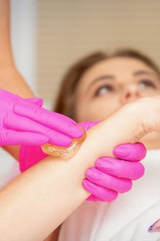 Waxing. Depilation hand and arm of the young woman lying in the spa salon