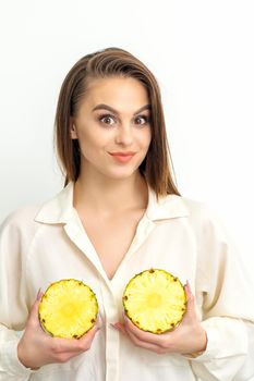 Young Caucasian smiling woman holding slices pineapple over white background, breast health concept