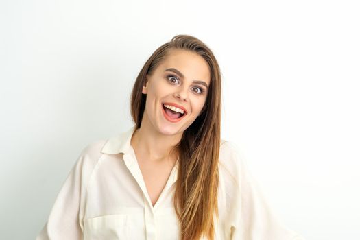 Portrait of a young caucasian happy woman wearing white shirt smiling with open mouth against the white background