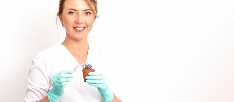 A smiling female beautician holds little green cactus with the razor in her hands. Hair removal concept