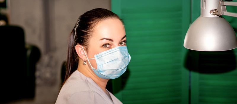 Young female podiatrist with a protective mask looking at the camera in her podiatry clinic