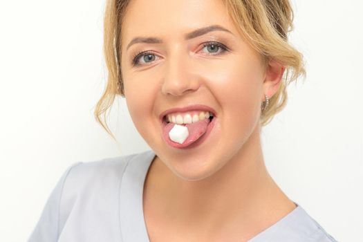 Waxing, depilation, hair removal concept. Happy young caucasian beautician with a sugar cube in her mouth looking at the camera on white background