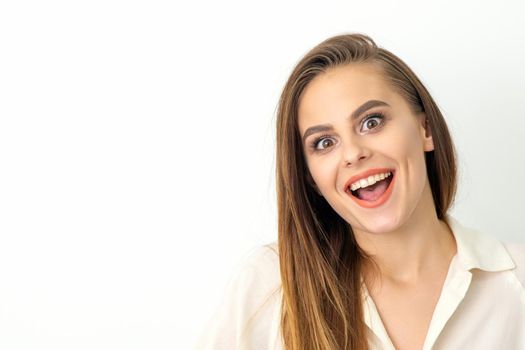Portrait of a young caucasian happy woman wearing white shirt smiling with open mouth against the white background