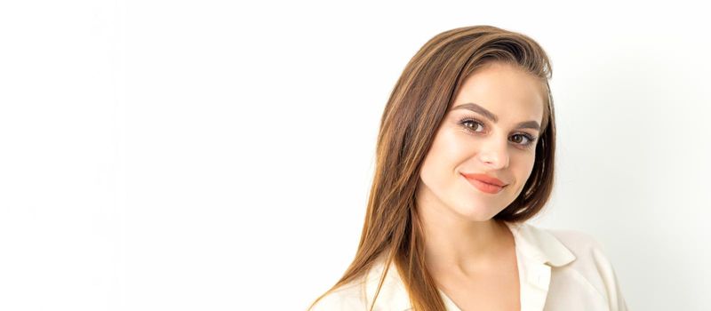 Portrait of a beautiful young caucasian smiling brunette woman with long straight hair standing and looking at the camera on white background