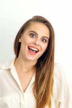 Portrait of a young caucasian happy woman wearing white shirt smiling with open mouth against the white background