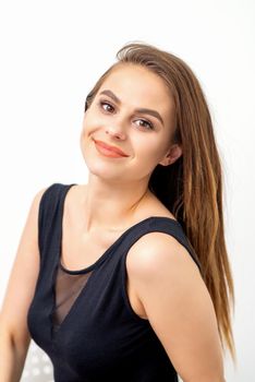 Portrait of a beautiful young caucasian smiling brunette woman with long straight hair standing and looking at the camera on white background