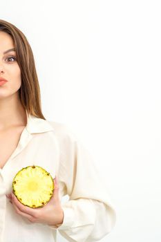 Young Caucasian smiling woman holding slices pineapple over white background, breast health concept