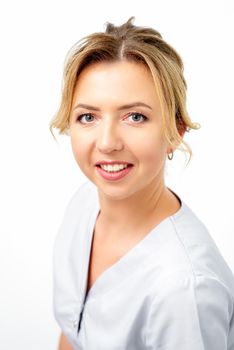 Close-up portrait of young smiling female caucasian healthcare worker standing staring at the camera on white background