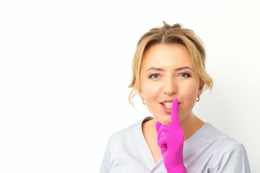 Young beautiful caucasian woman doctor, beautician doing silent gesture pressing his index finger to his lips isolated on white background