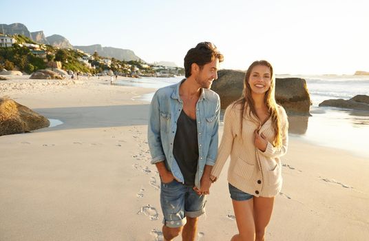 Leading him to a romantic spot on the beach. a romantic young couple walking hand in hand on the beach