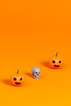 3d render of Halloween pumpkin and white skull on orange background
