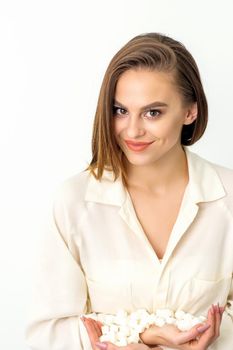 Portrait of young caucasian woman holding sugar cubes heap standing and looking at the camera against a white background