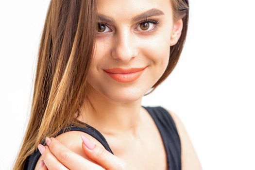 Portrait of a beautiful young caucasian smiling brunette woman with long straight hair standing and looking at the camera on white background