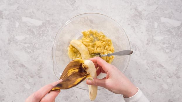 Flat lay. Step by step. Smashing riped bananas in a glass mixing bowl to prepare coconut banana pancakes.