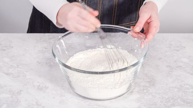 Step by step. Mixing ingredients in a glass mixing bowl to prepare coconut banana pancakes.