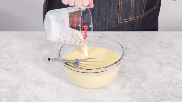 Step by step. Mixing ingredients in a glass mixing bowl to prepare coconut banana pancakes.