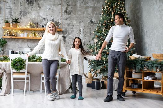 Merry Christmas and happy Holidays. Mom, dad and daughter decorating christmas tree