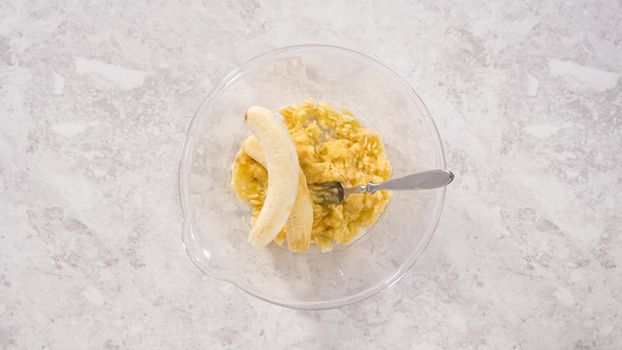Flat lay. Step by step. Smashing riped bananas in a glass mixing bowl to prepare coconut banana pancakes.