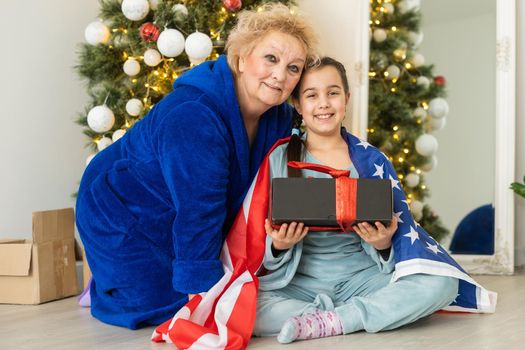 Family holding flag of USA at christmas. grandmother and granddaughter.