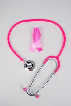Pink ribbon and stethoscope on a white background. The concept of the fight against breast cancer